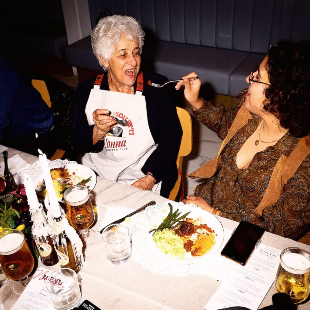 A fan offers a dish to a nonna from the club during a warm moment of sharing.